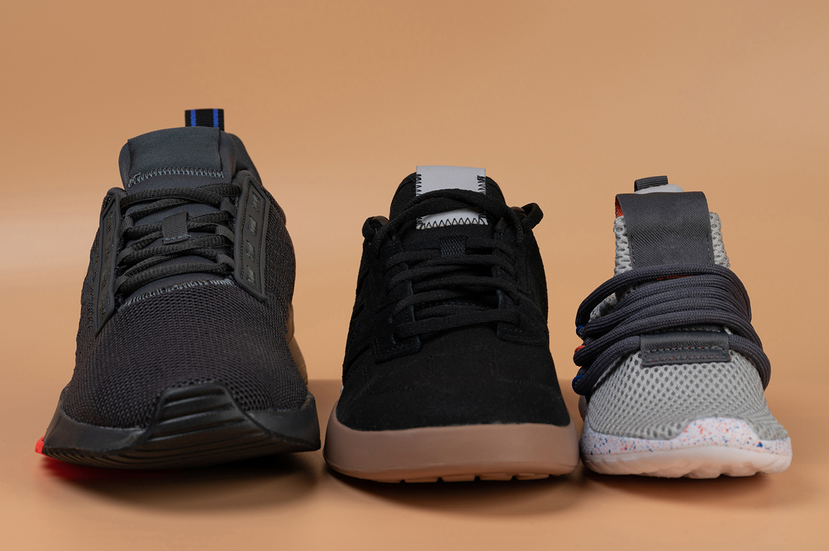 Different sized sneakers lined up in a row on a blank background.