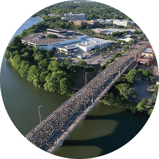 Austin’s oldest annual race the Capitol 10,000 overview shot of runners crossing the Congress Avenue bridge.