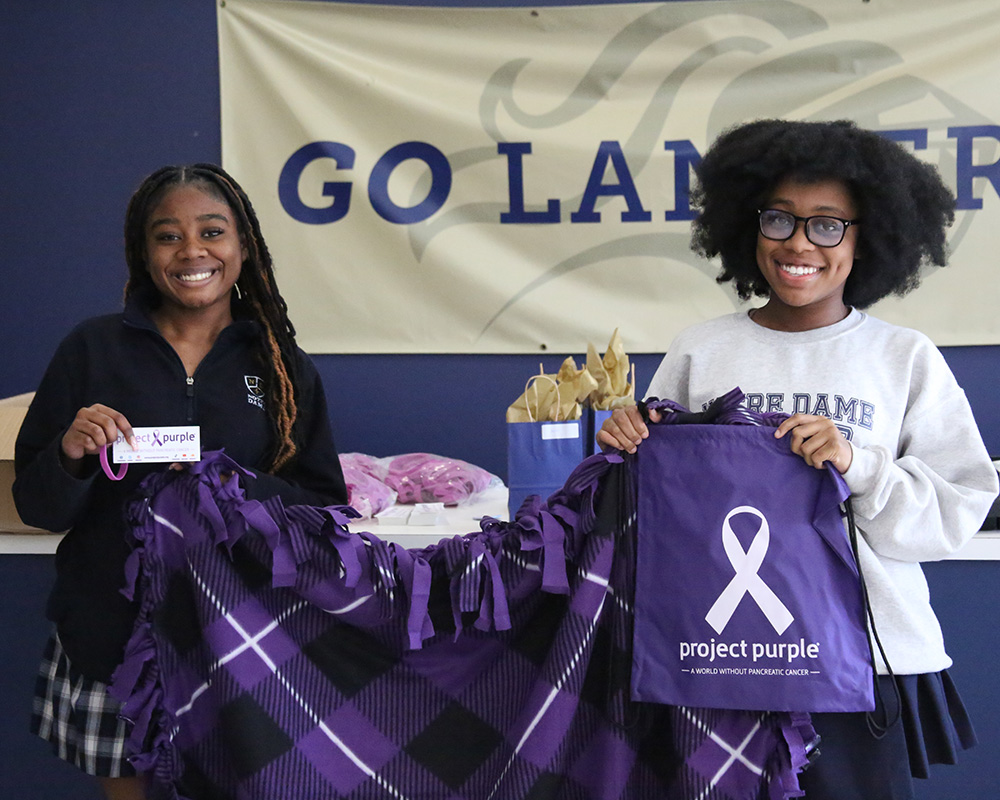 wo college girls at Notre Dame hold blankets for a Project Purple benefit.