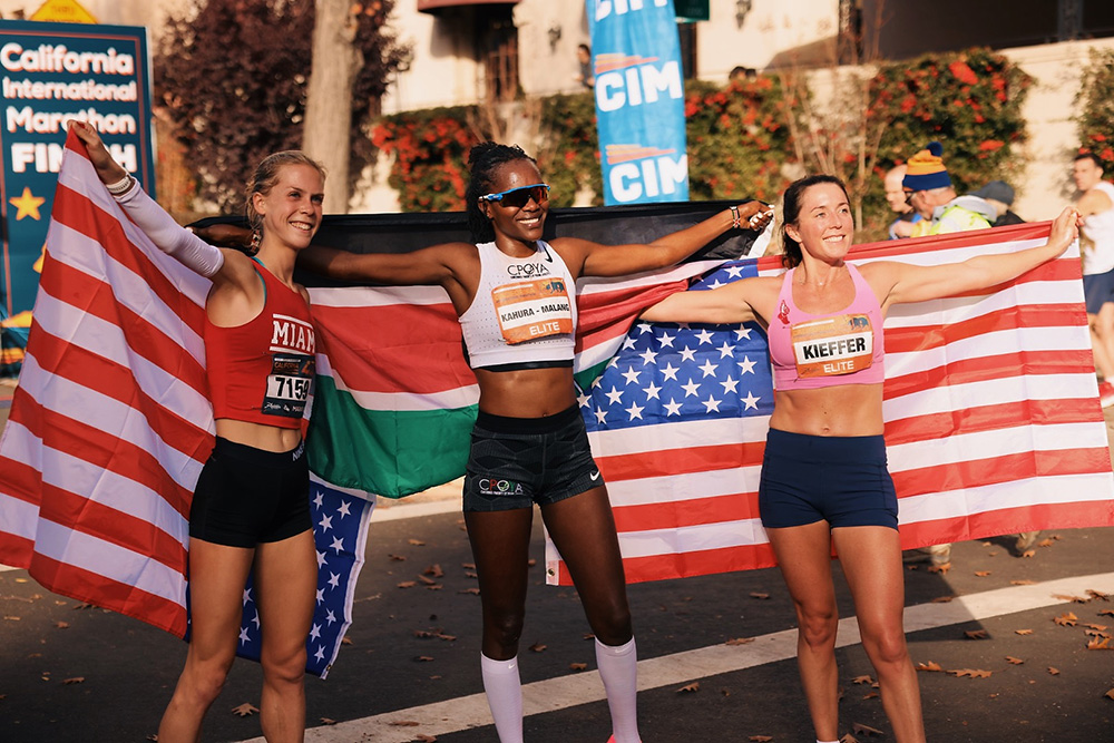 Winners of the 2023 California International Marathon race with an American flag celebrating winning and giving their sneakers a second life.
