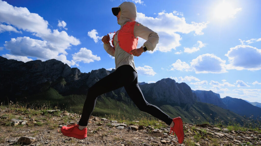 A female ultramarathon runner runs on a mountain top using her best ultramarathon shoes.