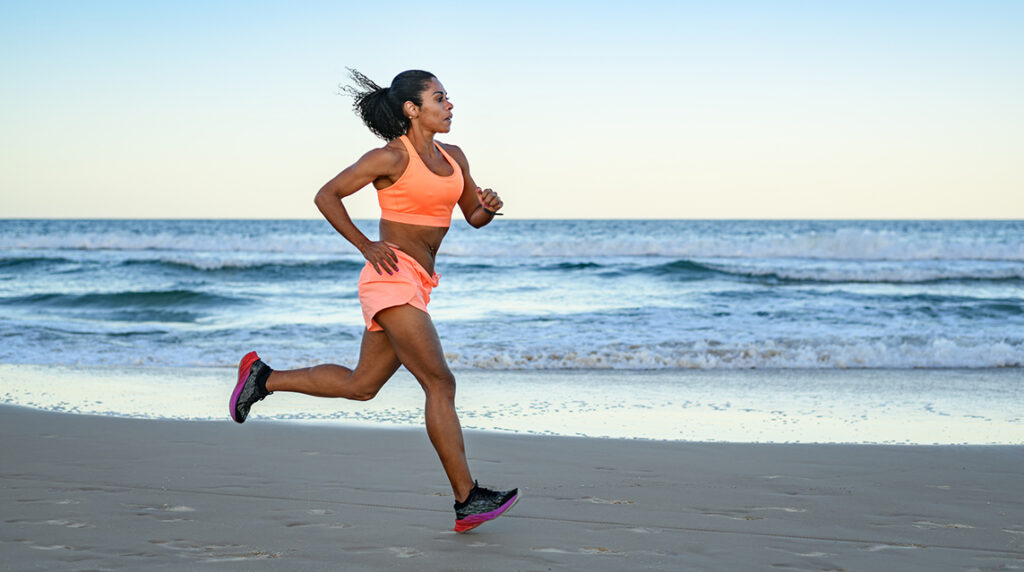 A woman in athletic clothing running on a beach.