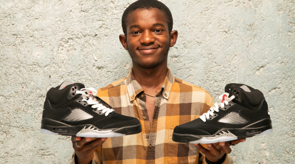 Haitian entrepreneur selling reused sneakers in a local market, supporting jobs sustainability through the reuse economy.