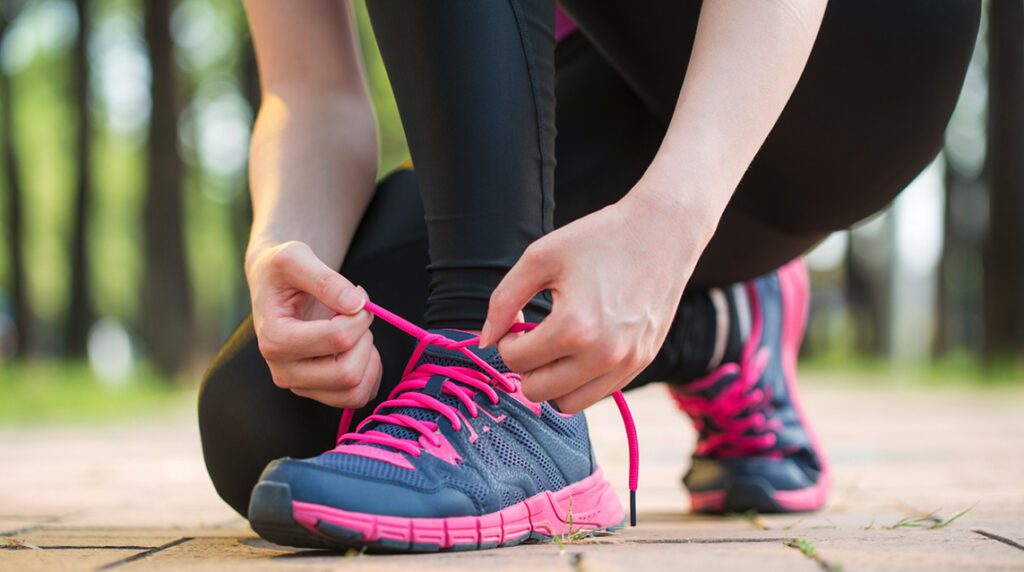 A woman is tying her running shoes before she goes on a run.